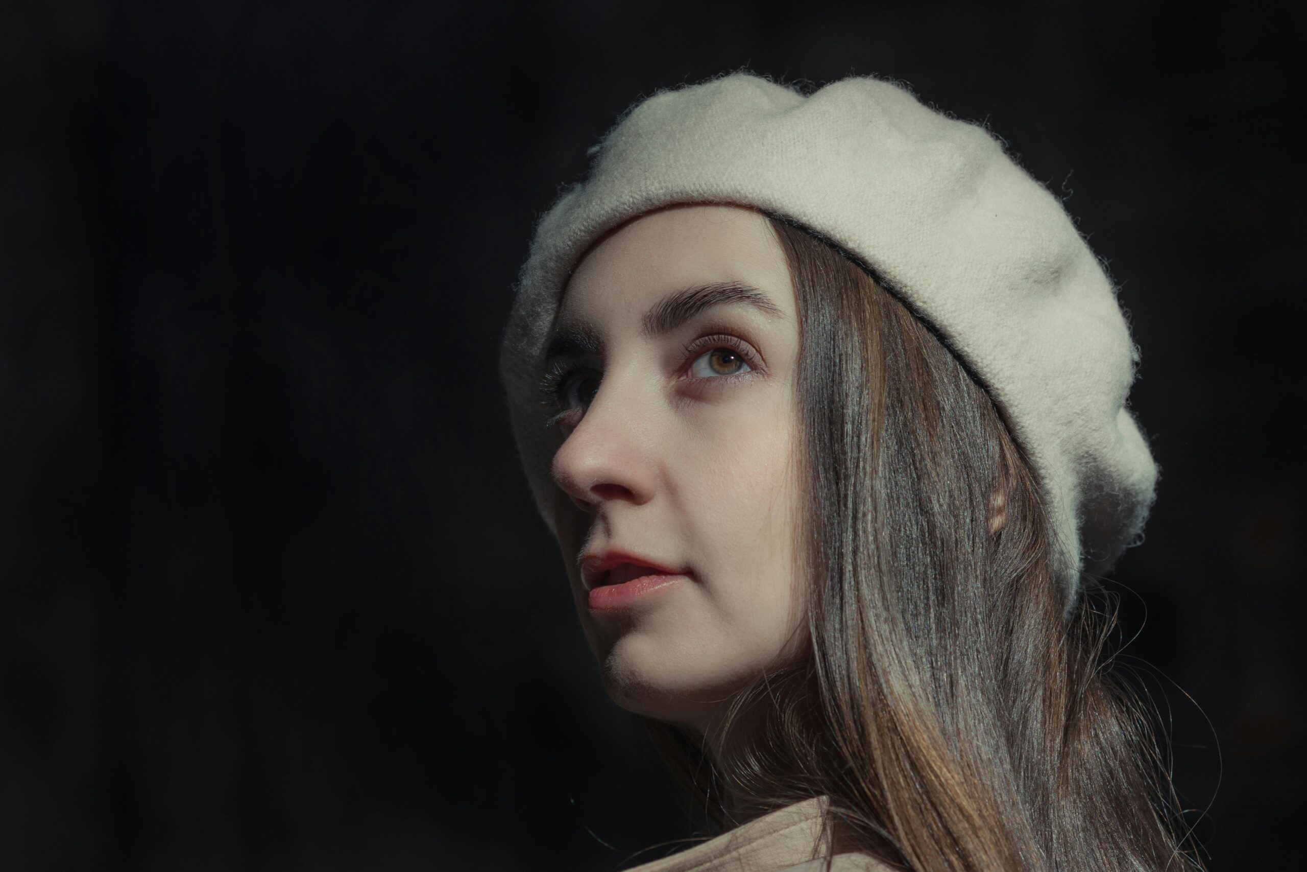 A stylish portrait capturing a young woman wearing a classic beret with a soft light background.